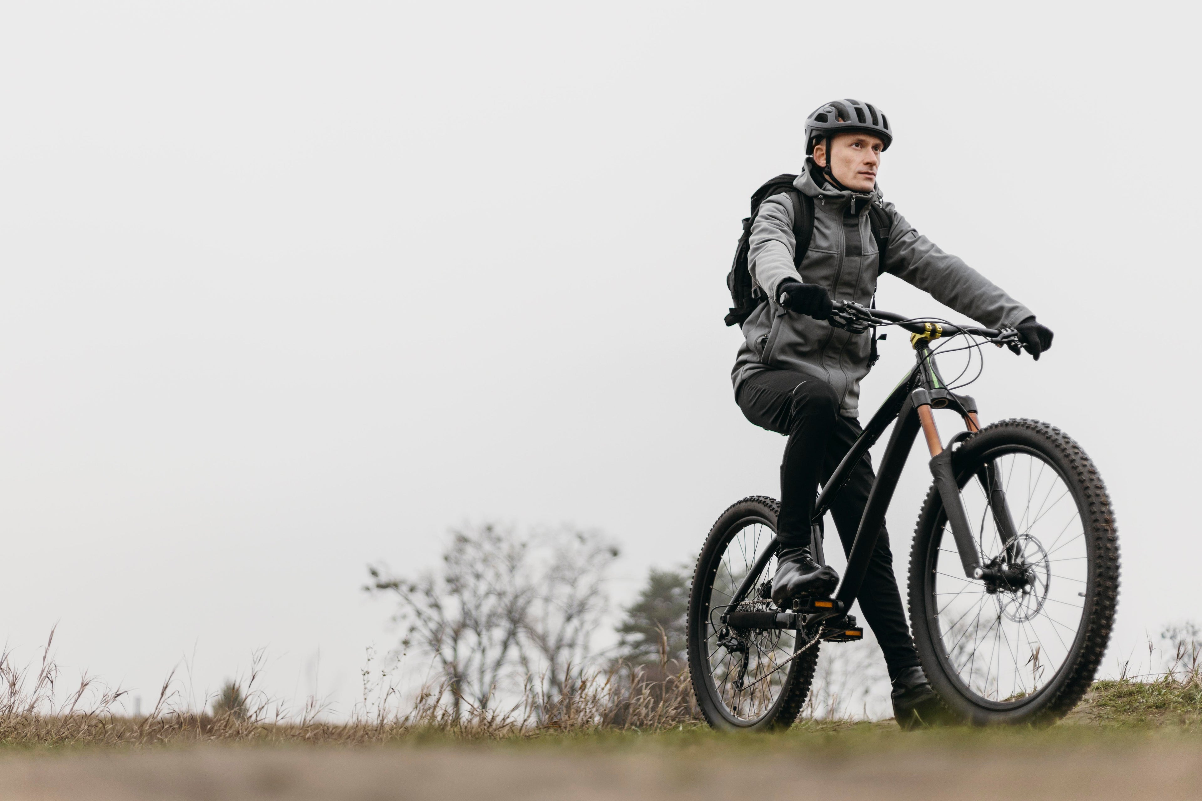 Person riding a mountain bike on a grassy field with a plain background