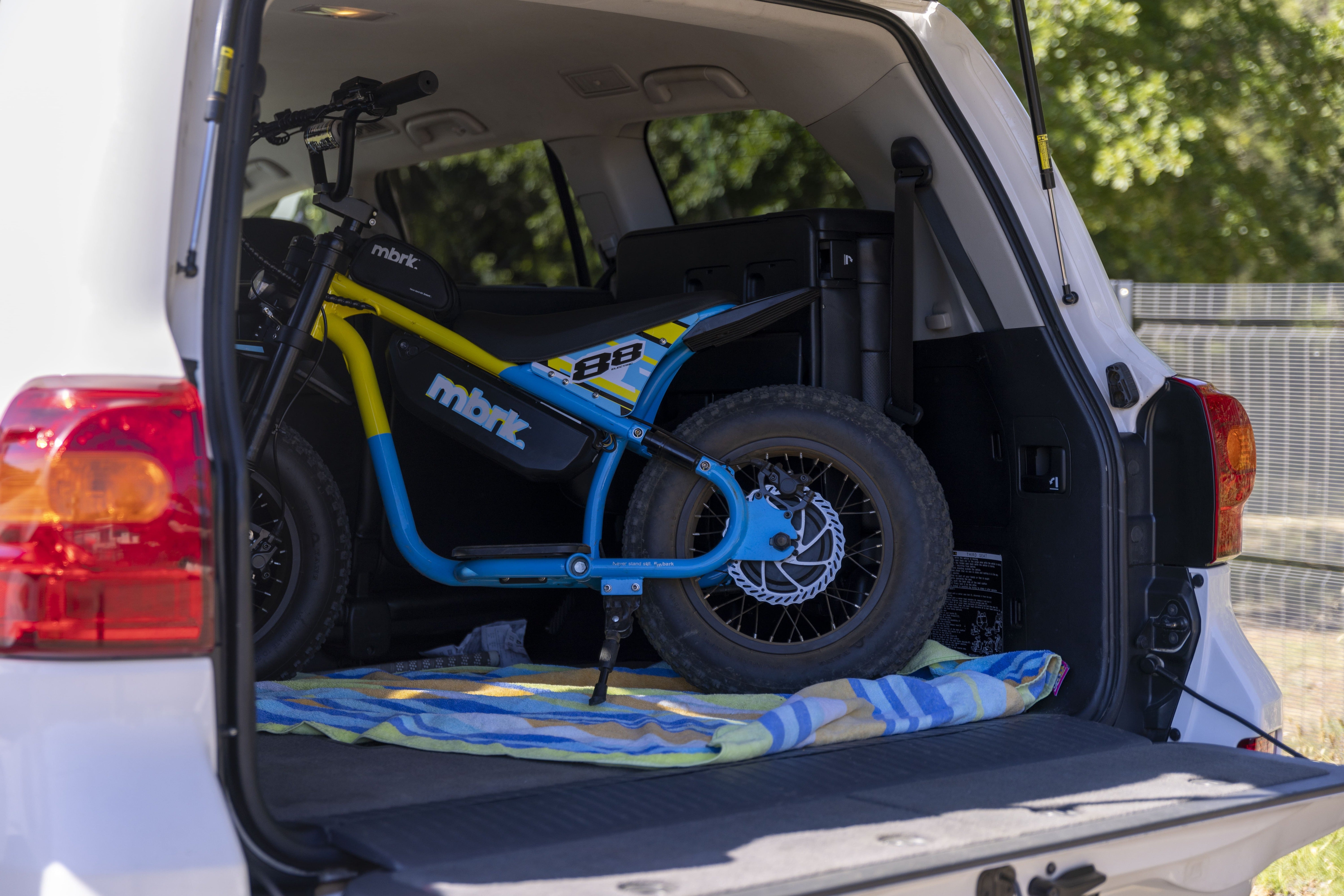 Electric bike on a colorful mat in the back of a white van with trees in the background